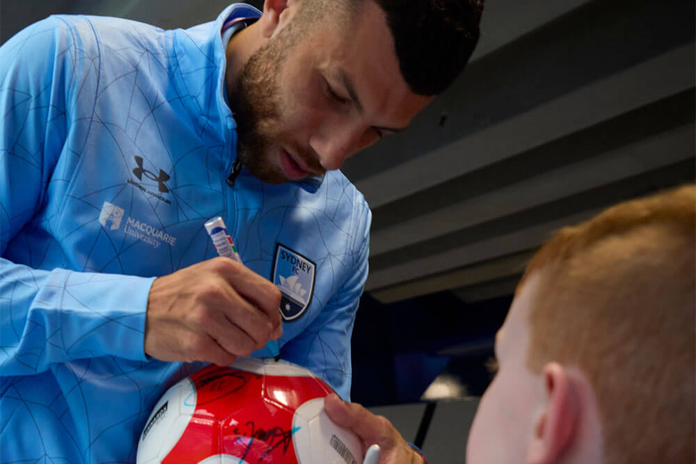 Sydney FC Player signing a Kennards Hire Kids Bay ball