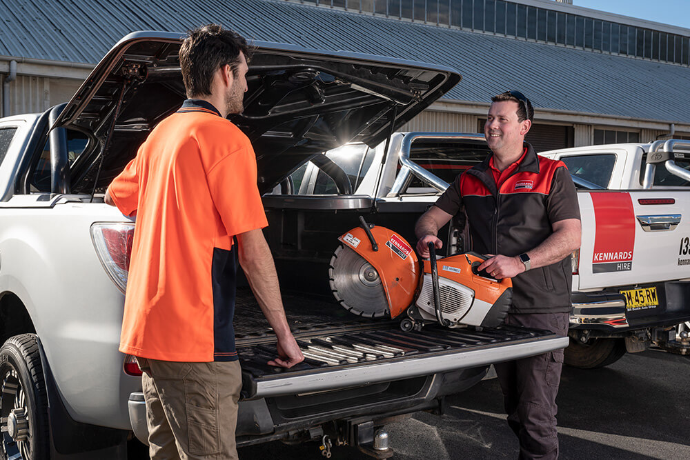Kennards Hire team member loading a demolition saw into a customers ute tray
