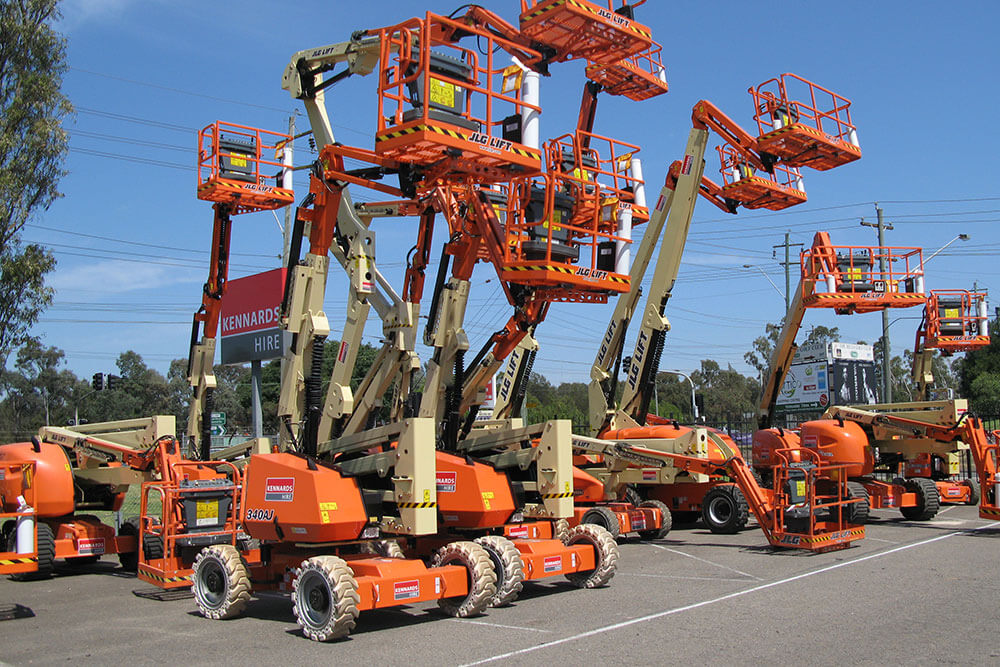 A row of boom lifts parked next to each other
