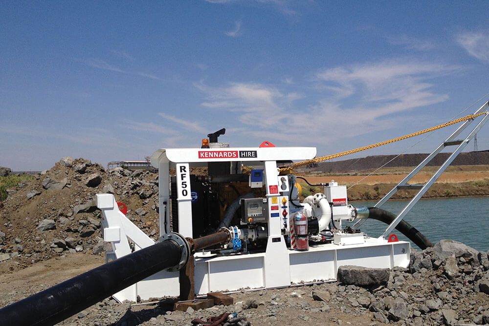 A large pump sitting on the edge of a site filled with water